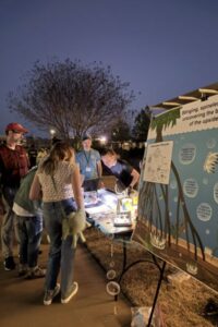 students showing poster to guests at booth